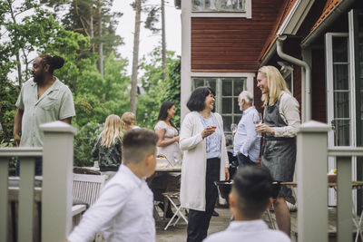 Women talking with each other holding wineglass during dinner party