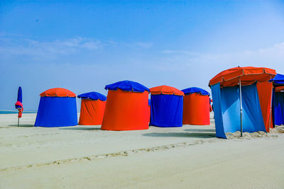 Multi colored umbrellas on beach against blue sky