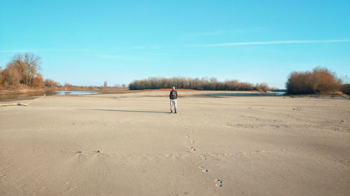 Rear view of man standing on land against sky