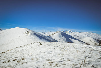 Scenic view of snowcapped mountains against clear blue sky