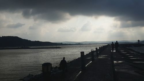 Pier on sea against cloudy sky