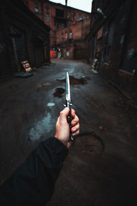 Man holding umbrella on street in city