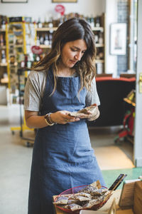 Female employee checking food products while standing in deli