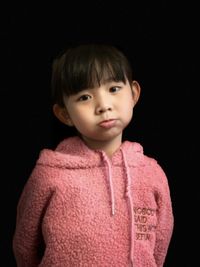 Portrait of cute boy against black background