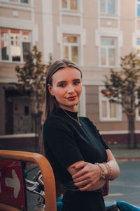 Portrait of smiling young woman standing against building