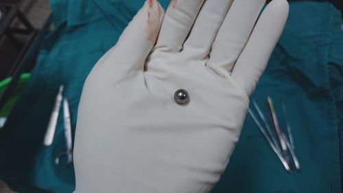 Cropped hand wearing glove holding metal