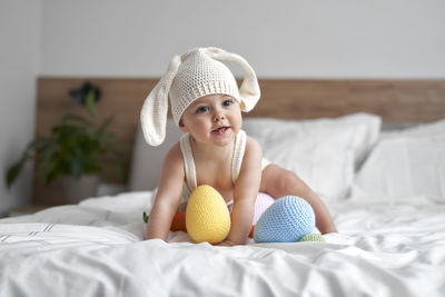 Cute girl playing with easter toys on bed at home