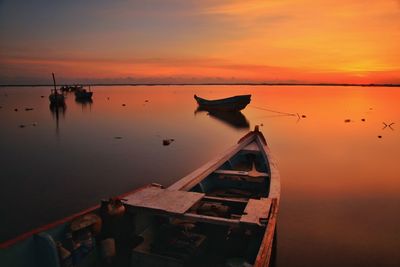 Boats moored on sea against sky during sunset