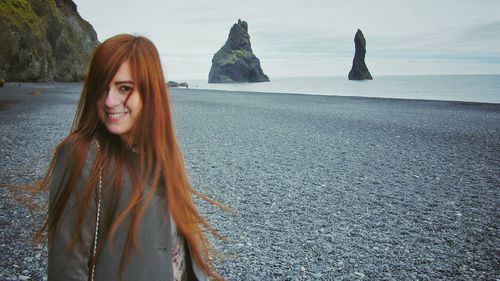 Portrait of beautiful young woman standing at beach