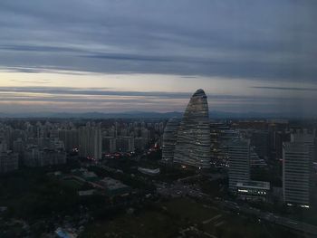 Aerial view of city at waterfront against cloudy sky