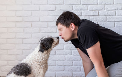 Young man with dog against wall