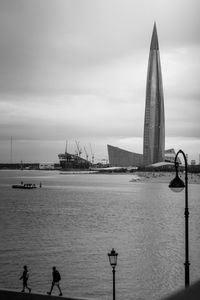 Sailboats in sea against cloudy sky