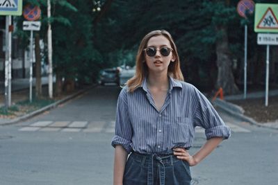 Portrait of young woman standing on road in city