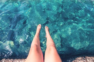 Low section of woman relaxing in swimming pool