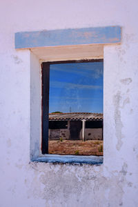 Buildings against blue sky seen through window