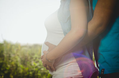 Midsection of man embracing pregnant woman while touching abdomen