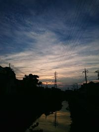 Electricity pylon against cloudy sky