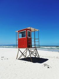 Lifeguard hut on beach against clear blue sky