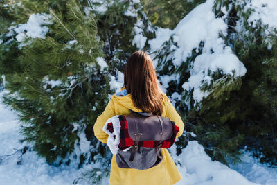 Rear view of woman in snow covered trees during winter