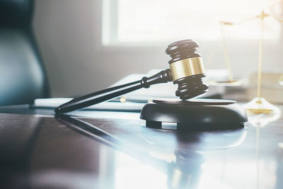 Close-up of gavel on table against window in office