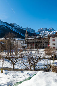 Snow covered buildings and mountains against sky