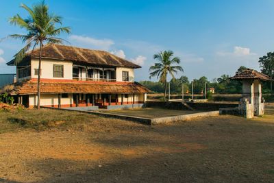 House by palm trees and building against sky