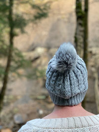 Rear view of woman wearing a knit hat walking in woodlands