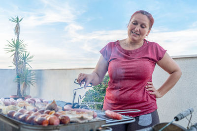 Woman preparing food on barbeque grill in balcony