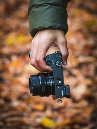 Cropped hand holding digital camera outdoors