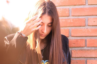 Portrait of beautiful young woman against brick wall