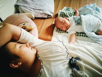 High angle view of father with baby sleeping on bed