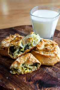 Baked twisted patties with dock and white cheese served for consumption with a glass of milk