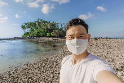 Man with face mask has a summer sea trip while in covid-19 pandemic.