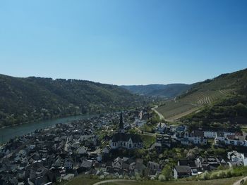 Aerial view of townscape and mountains against clear blue sky