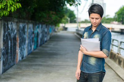 Young woman standing against wall in city