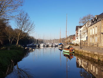 Sailboats moored on canal amidst buildings against clear sky