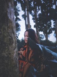 Woman standing by tree in forest