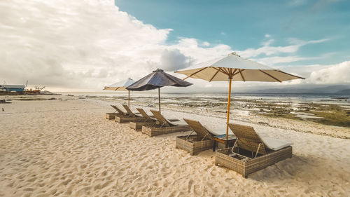 Deck chairs on beach against sky