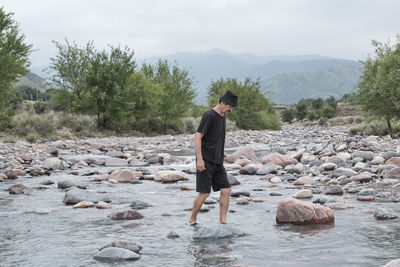 Senior man crossing shallow rocky mountain river