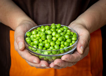 Midsection of woman holding green peas