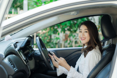 Portrait of smiling woman sitting in car