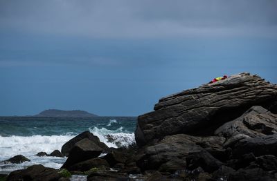 People on cliff by sea against sky