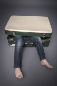 Low section of woman with suitcase against wall