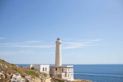 Lighthouse by sea against sky