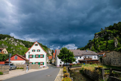 Road amidst buildings against cloudy sky