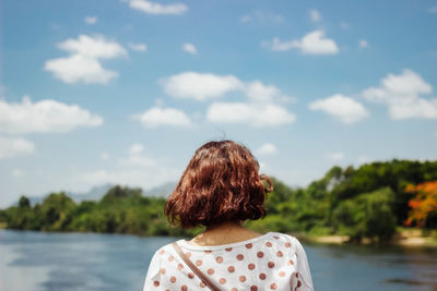 Rear view of woman looking at lake against sky