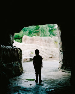 Rear view of silhouette man standing in cave