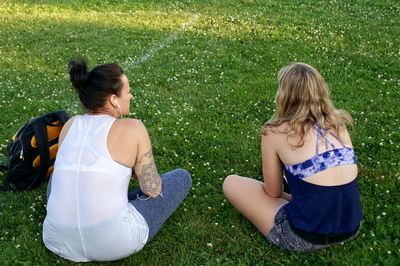 Two women sitting on grassy field