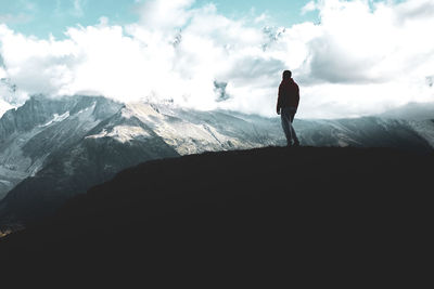 Silhouette man standing on mountain against sky