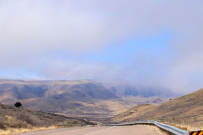 Scenic view of road by mountains against sky